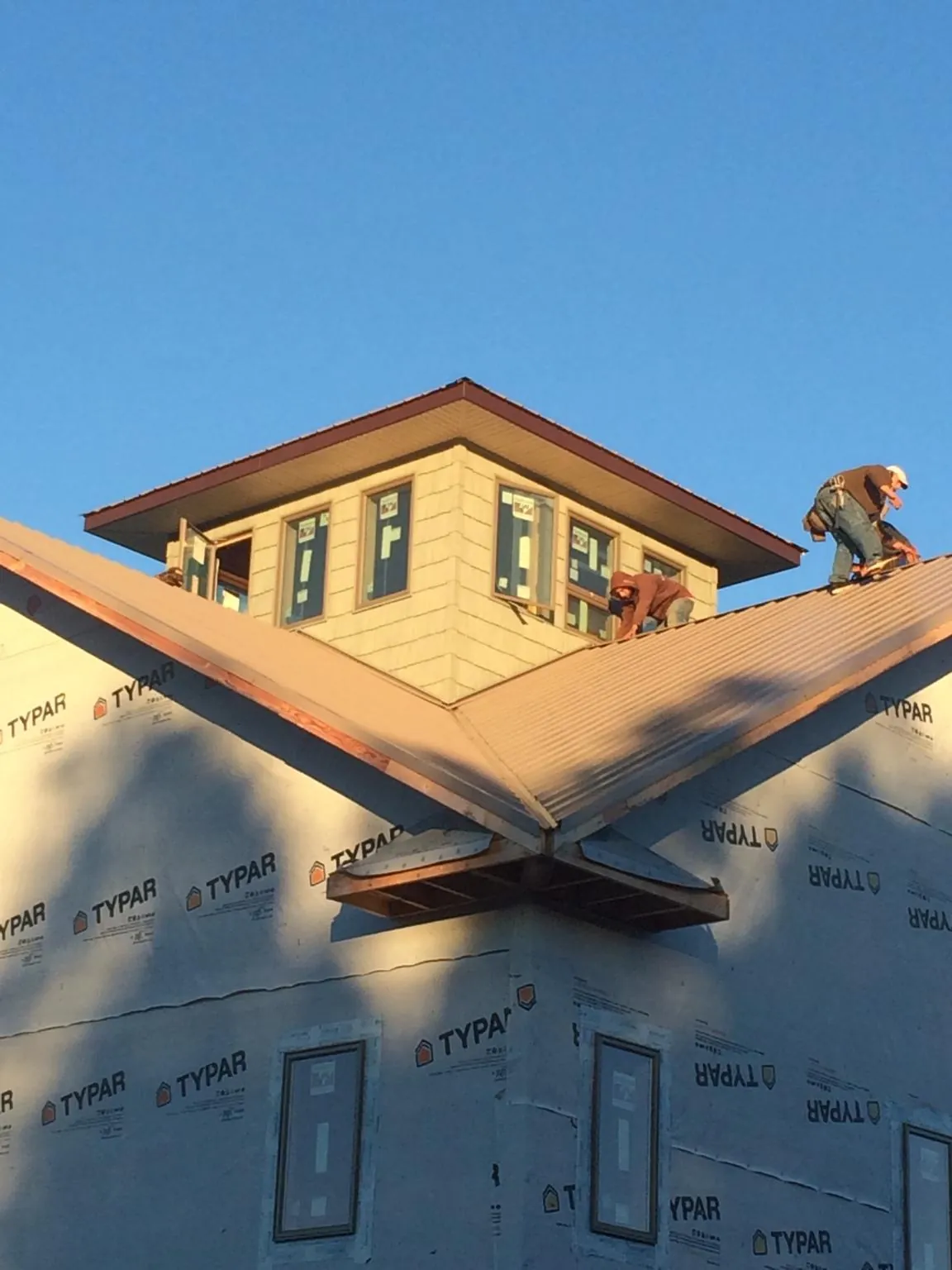 Roofers working around a rooftop cupola on a new metal roof at sunset — Roof Waterproofing in Oakwood by Roofing Brothers